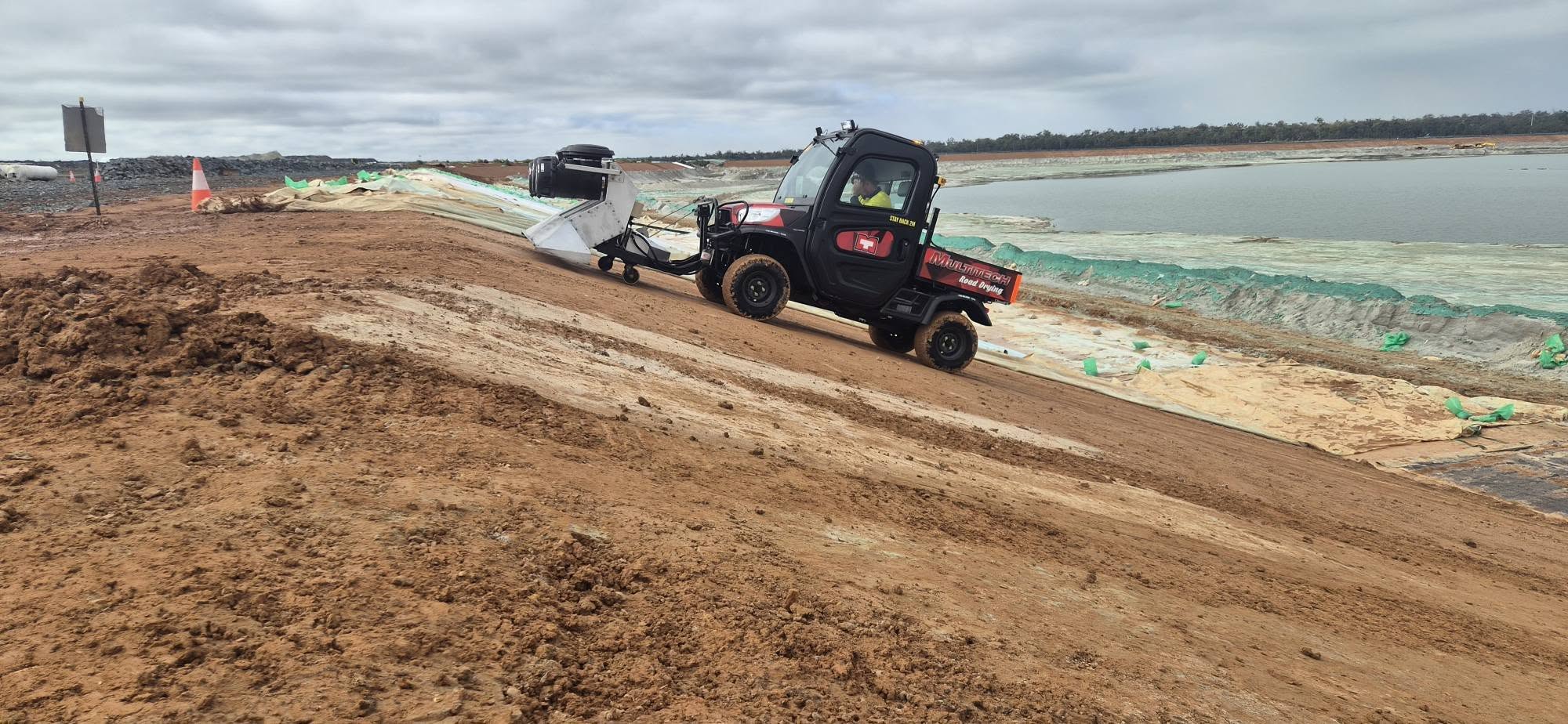 Multitech road dryer towing its drying head along a dirt haul road in daylight
